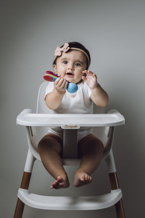 a baby girl sitting in a baby chair