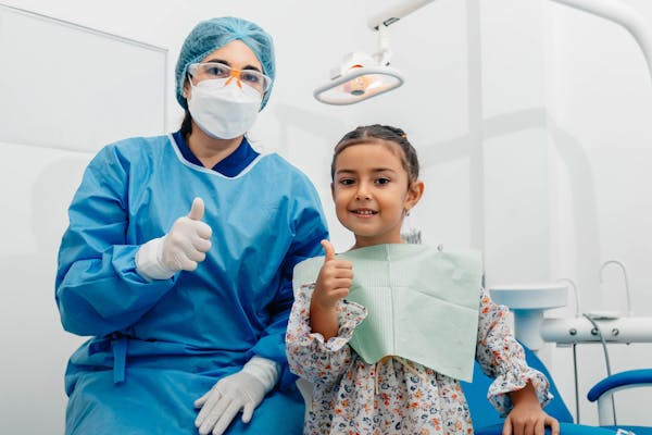 photo of a dentist and a little girl showing a thumbs up