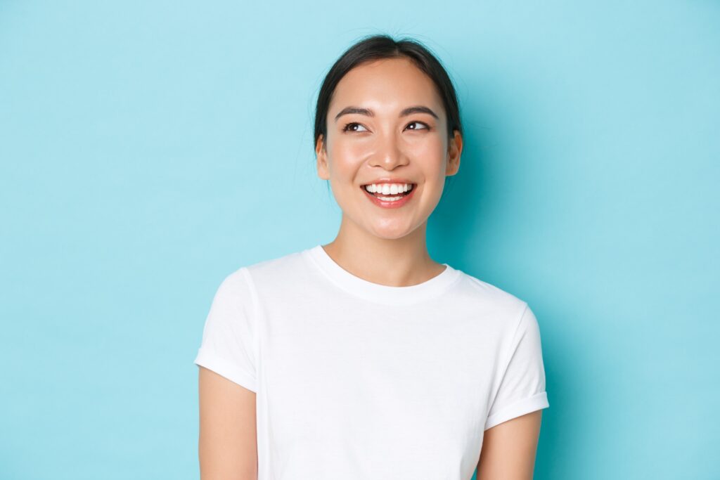 a woman in a white shirt smiling against the teal background min