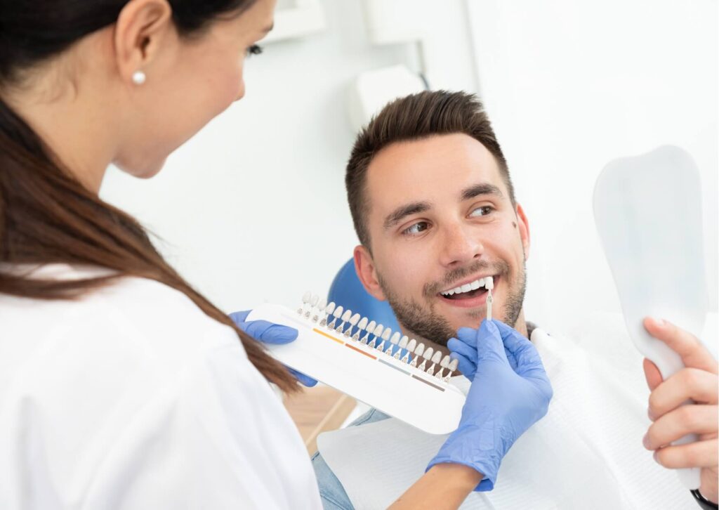 Dentist comparing tooth shades with a patient during a consultation about teeth whitening options and expected whitening results.