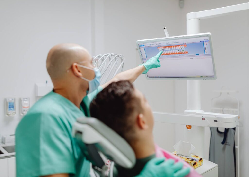 Dentist reviewing digital dental images with a patient to identify cavities and explain what a cavity looks like on a tooth during an exam.