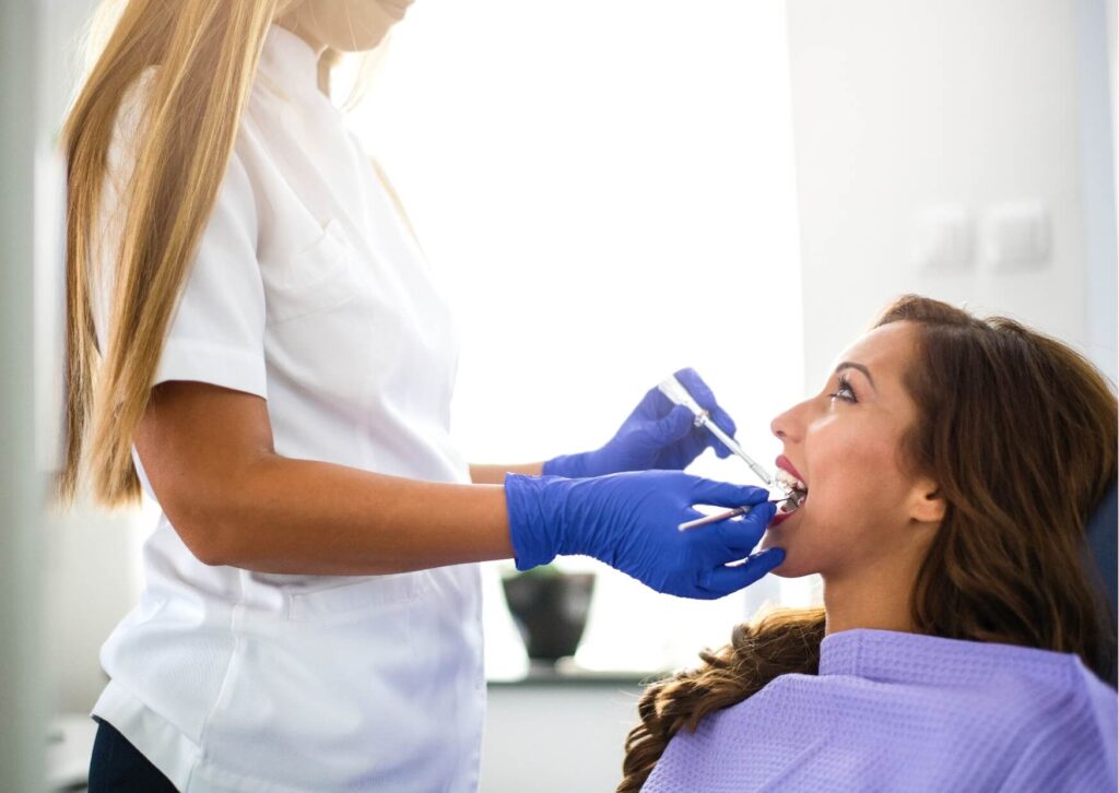 Dentist examining a patient's gums during a dental visit to evaluate receding gums and recommend appropriate treatment.
