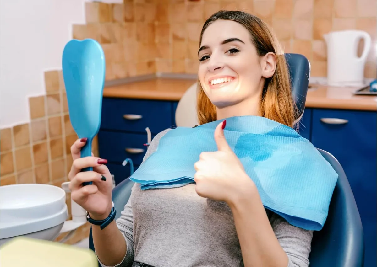 Dental patient examining her teeth in a mirror after a checkup for cavities and tooth decay.