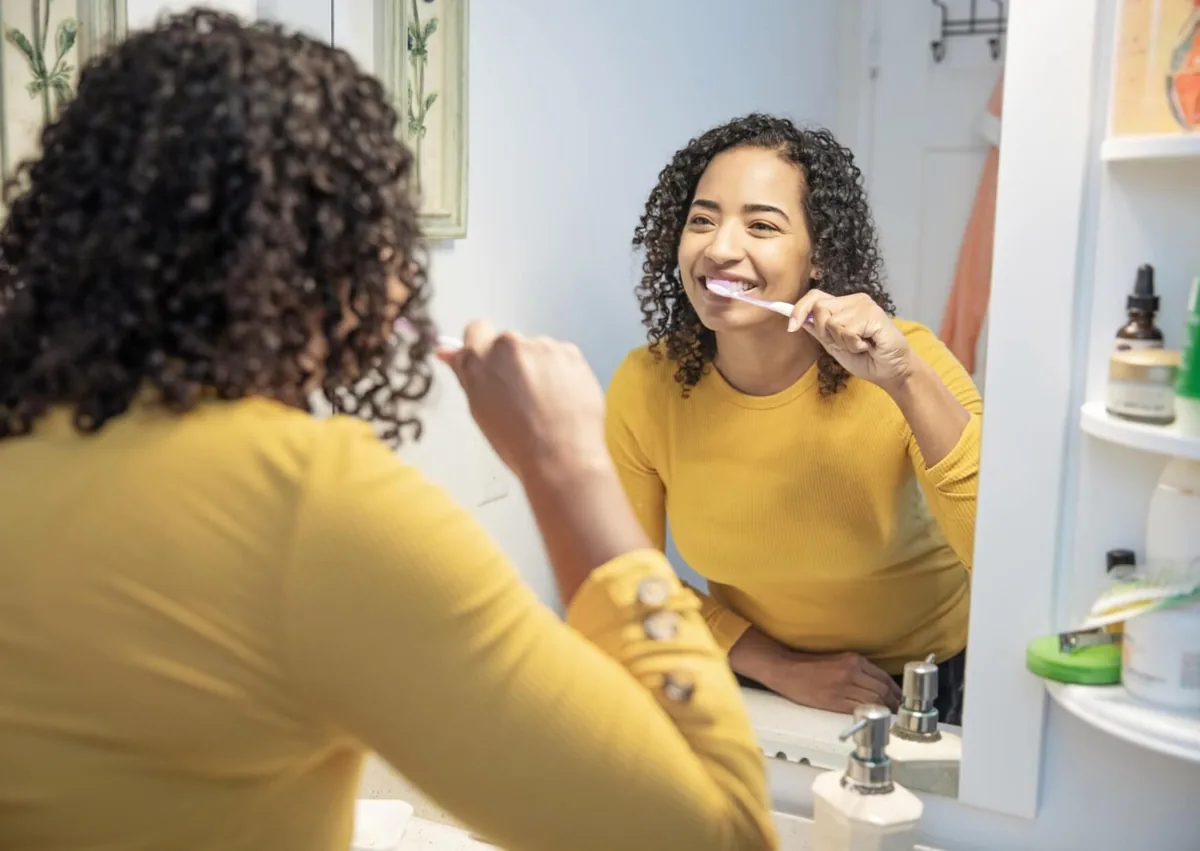 Woman brushing her teeth as part of daily oral care after teeth bonding.